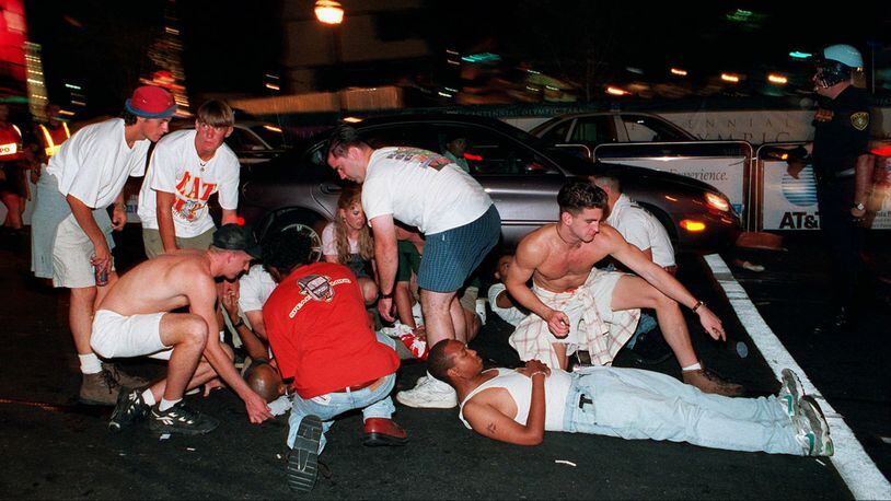 Spectators tend to injured victims following an early morning explosion in Atlanta's Olympic Centennial Park Saturday, July 27, 1996. The downtown park was crowded with Olympic visitors and revelers at the time of the explosion, which killed a woman and injured more than 100 other people.