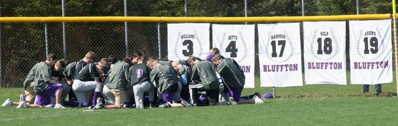 The Bluffton University baseball team pauses near the numbers of their fallen teammates before the start of their first game back since a tragic bus accident in Atlanta. Staff photo by Chris Stewart