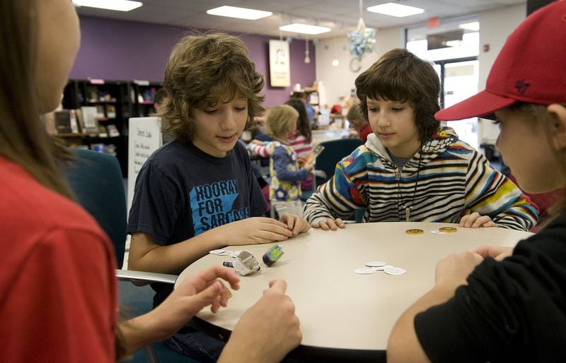 Right to left, Alex Brown, 11, Gabriel Brown, 11 and Eli Cox, 9, play the dreidel game, a traditional Hanukkah game, at the Dreidel Tournament held at Recycled Reads in 2013.