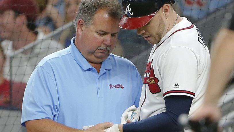Freddie Freeman is examined after being hit by a pitch in the fifth inning of Wednesday’s game at SunTrust Park. (John Bazemore/AP photo)