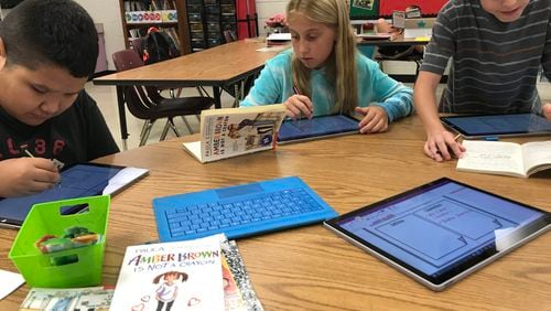 Holly Springs students (left to right) Matthew Rodriguez-Pineda, Klaire Henkle and Maximillian Raiford use technology to illustrate their reading. The Cherokee County school is also a STEM academy.