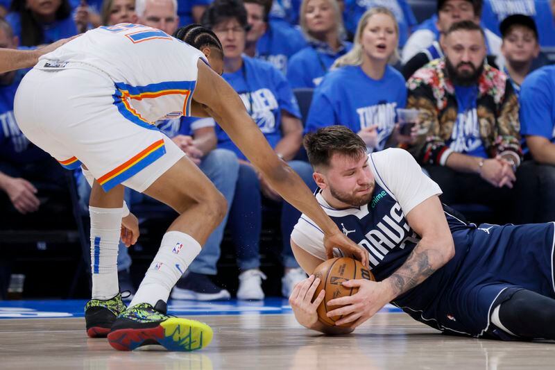 Dallas Mavericks guard Luka Doncic, right, and Oklahoma City Thunder guard Aaron Wiggins scramble for a loose ball during the first half of Game 1 of an NBA basketball second-round playoff series, Tuesday, May 7, 2024, in Oklahoma City. (AP Photo/Nate Billings)