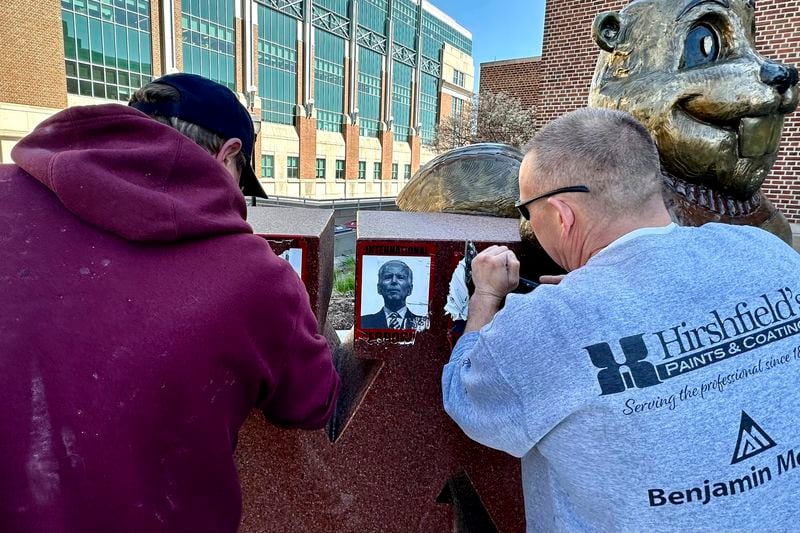 Workers remove posters with an image of President Joe Biden reading, "International Terrorist," from a statue on the University of Minnesota campus, Wednesday, April 24, 2024, in Minneapolis. Student activists called for a second day of protest against Israeli military action in Gaza. (AP Photo/Mark Vancleave)