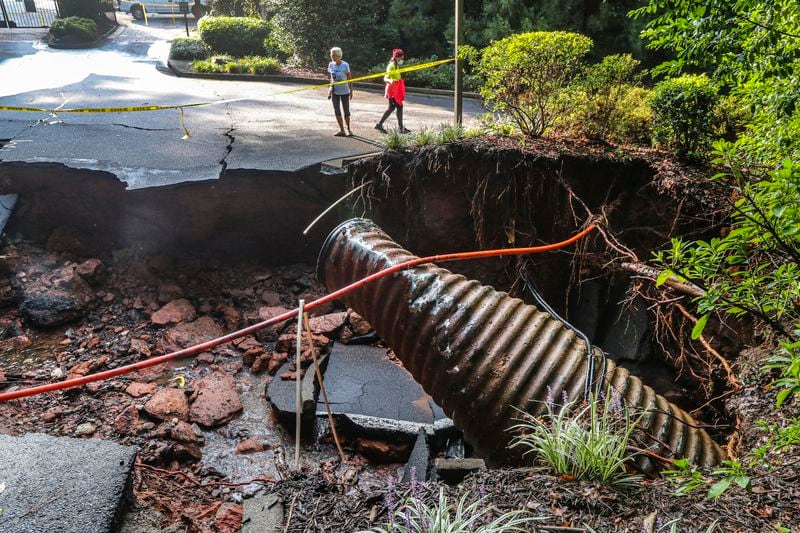 Onlookers overlook the road that was washed away at Fawn Place at East Lake Parkway in Marietta on Wednesday, Sept. 8, 2021, after torrential downpours of rain overnight brought flooding and damage to the Cobb County area.  (John Spink / John.Spink@ajc.com)