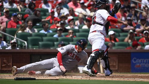 Boston Red Sox's Garrett Cooper, left, slides safely into home plate for a run ahead of the tag by St. Louis Cardinals catcher Pedro Pages, right, in the fourth inning of a baseball game Sunday, May 19, 2024, in St. Louis. (AP Photo/Joe Puetz)