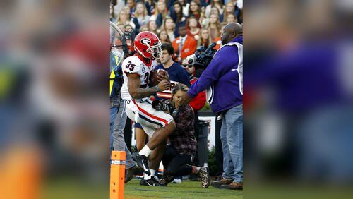 Georgia running back Brian Herrien (35) runs out of bounds and into a photographer during the first half of an NCAA college football game against Auburn, Saturday, Nov. 16, 2019, in Auburn, Ala.