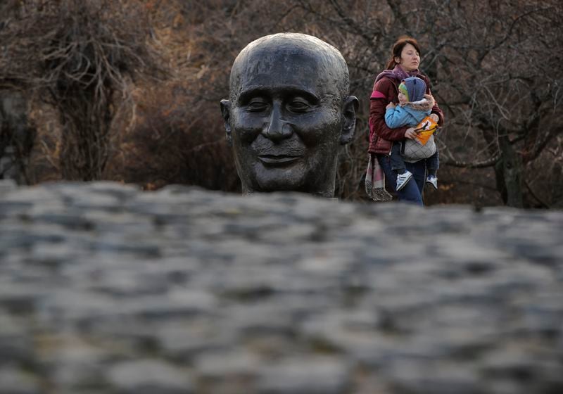 FILE - A woman walks holding a baby by a sculpture depicting French diplomat Jean Monnet, part of the monument of the European Union Founding Fathers in Bucharest, Romania, on Dec. 29, 2018. The European Union marks Europe Day on Thursday, May 9, but instead of the traditionally muted celebrations, all eyes are on the EU elections in one month time which portend a steep rise of the extreme right and a possible move away from its global trendsetting climate policies. (AP Photo/Vadim Ghirda, File)