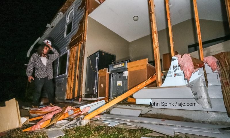 Ontario Alvarez surveys storm damage in front of his mother's house on Jumpers Trail in Fairburn. JOHN SPINK / JSPINK@AJC.COM