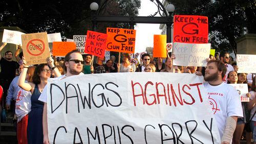 Opponents of Campus Carry march at the University of Georgia arch. TAYLOR CARPENTER / TAYLOR.CARPENTER@AJC.COM