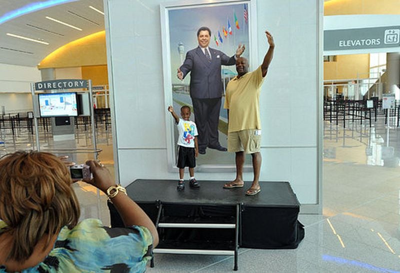 Glenn Thomas, right, of Lithonia, and his 6-year-old son Myles pose in front of Maynard H. Jackson Jr.'s portrait when the international terminal opened in 2012. (Hyosub Shin/hshin@ajc.com)