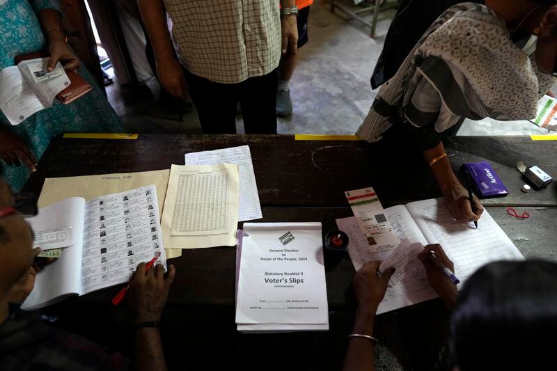 A voter shows her identity papers and signs her name in the polling register before casting her vote during the second round of voting in the six-week-long national election near Palakkad, in Indian southern state of Kerala, Friday, April 26, 2024. (AP Photo/Manish Swarup)
