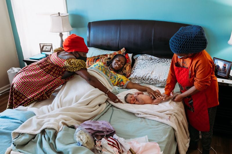Rimani Kelsey-Rogers, center, greets her new daughter Sadia shortly after giving birth in her Atlanta home on Dec. 18, 2020. Midwives Nasrah, left, Sarahn Henderson, right, help tend to the new baby. Photo by Chanda Williams / thebirthstorycollective.com