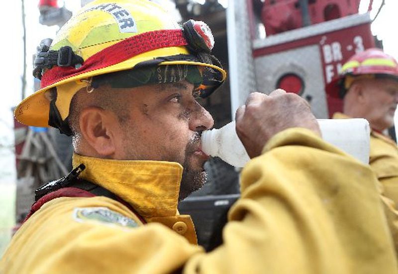 Mark Tabarez takes a water break from fighting the Rock Mountain fire in Rabun County. CURTIS COMPTON / CCOMPTON@AJC.COM