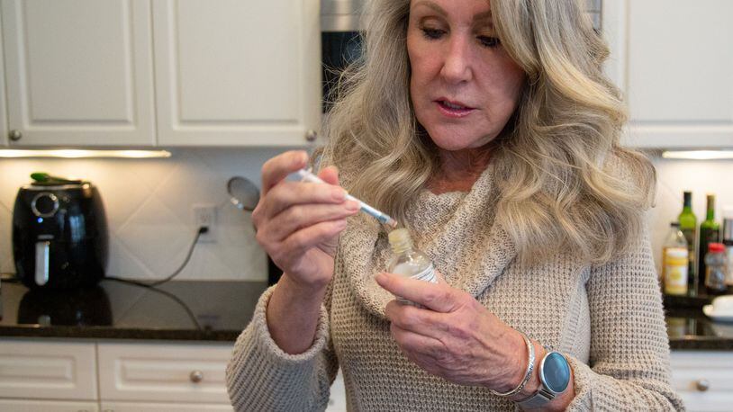 Cindy Dawson prepares her morning dose of low THC oil in the kitchen of her Smyrna home in December 2019. The Georgia Access to Medical Cannabis Commission on Wednesday unanimously approved licenses for two companies authorizing them to grow, manufacture and sell marijuana oil in Georgia within the year. STEVE SCHAEFER / SPECIAL TO THE AJC