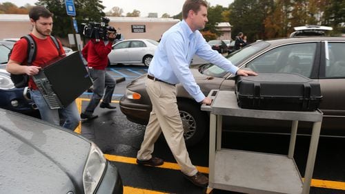 Investigators take a voting machine and a desktop computer from the DeKalb County elections office on Thursday. (Ben Gray / bgray@ajc.com)