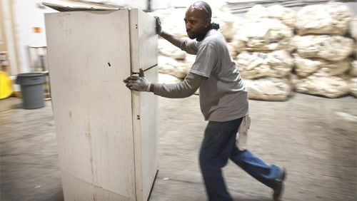 A man pushes a fridge into an appliance recycling center in this file photo.