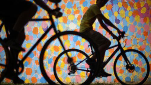 Bicyclists cruise along the Beltline past a mural by HENSE under Virginia Avenue. Ben Gray / bgray@ajc.com