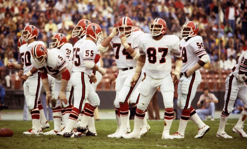 The Atlanta Falcons defense, including linebackers Greg Brezine (50). Ralph Ortega (55), and Robert Pennywell (59), and defensive linemen Jeff Merrow (75), Wilson Faumina (74), and Claude Humphrey (87), wait for the snap in 1977.