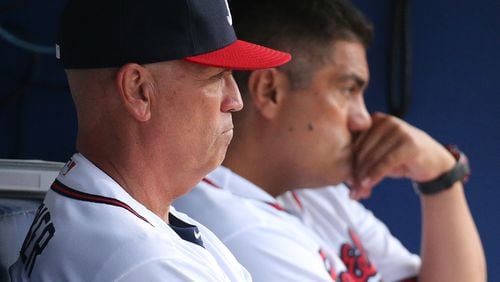 Braves first-base coach Eddie Perez (right) and manager Brian Snitker look on from the dugout during a game at Turner Field this past season. (Curtis Compton / ccompton@ajc.com)