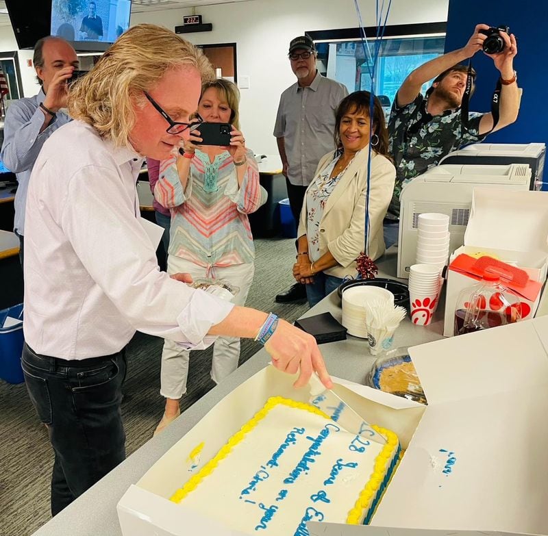 Chris Camp cuts his going-away cake at WSB radio May 31, 2022, his final day as news director at the station after more than 28 years at the helm. MARK MCKAY