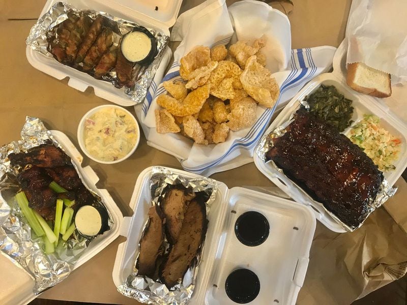 Bub-Ba-Q offers championship barbecue. Pictured, clockwise from left: wings with sweet and spicy sauce, a pint of potato salad, Bubba Penos, pork rinds, half-rack of baby back ribs with collards and coleslaw, half-pound of smoked brisket. LIGAYA FIGUERAS / LIGAYA.FIGUERAS@AJC.COM