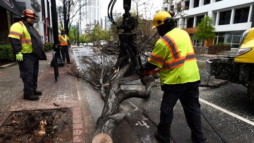 A crew from the Atlanta Forestry Division works to remove a tree that fell on top of a van at the intersection of Peachtree Street and 3rd Street. HENRY TAYLOR / HENRY.TAYLOR@AJC.COM