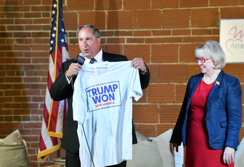John Fredericks, the host of "The John Fredericks Show," holds a “Trump Won” T-shirt with Suzi Voyles, a Republican candidate in the 6th Congressional District, at his side Tuesday during a rally in Rome. (Hyosub Shin / Hyosub.Shin@ajc.com)