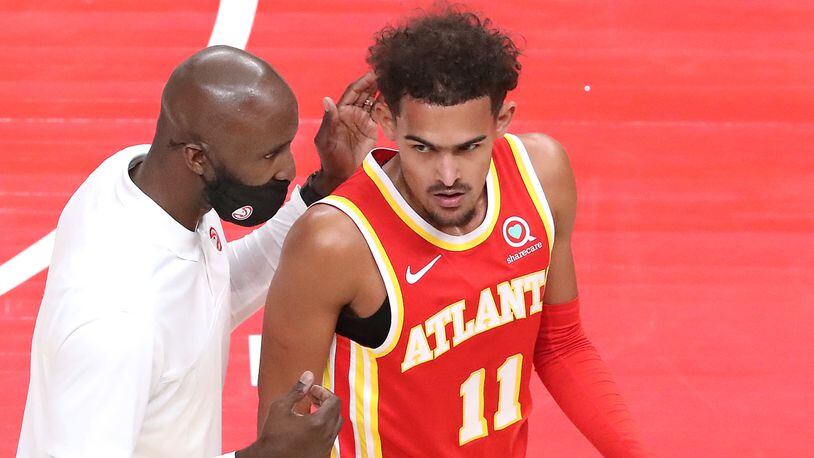 122820 ATLANTA: Atlanta Hawks head coach Lloyd Pierce confers with Trae Young during first half of the home opener against the Detroit Pistons Monday, Dec. 28, 2020, at State Farm Arena in Atlanta.  (Curtis Compton / Curtis.Compton@ajc.com)