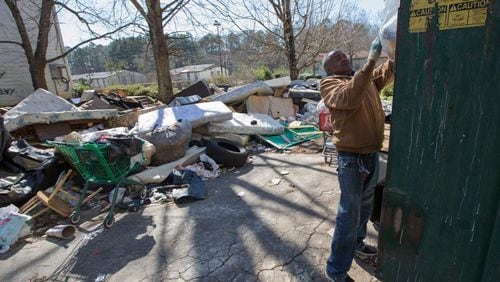 In this photo from February 2016, resident James Starr, who had lived at Brennon Hill for four years, puts his trash in a Dumpster despite trash and debris everywhere on the property. The site was later condemned and now the demolition will be complete. AJC file photo