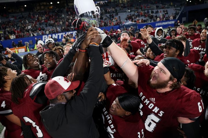 Warner Robins coach Marquis Westbrook celebrates with the trophy with players after their 62-28 win against against Cartersville in the Class 5A state high school football final at Center Parc Stadium Wednesday, December 30, 2020 in Atlanta. JASON GETZ FOR THE ATLANTA JOURNAL-CONSTITUTION