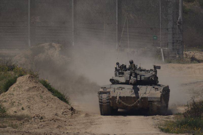 An Israeli soldier moves atop a tank near the Israeli-Gaza border as seen from southern Israel, Thursday, April 4, 2024. (AP Photo/Leo Correa)