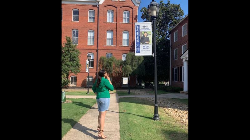 Spelman College senior Kayla Smith stares at a poster of herself on the campus. The college moved all classes online for the fall 2020 semester, limiting opportunities for Smith to celebrate her final year at the school on campus. PHOTO CONTRIBUTED.