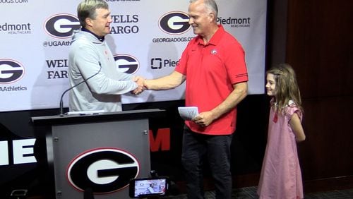 Georgia coach Kirby Smart (left) welcomes former Bulldogs coach Mark Richt and his granddaughter Jadyn to Monday's press conference. Scheduled to discuss the No. 1 Bulldogs' game against No. 22 Kentucky on Saturday, Richt borrowed the podium to promote his Oct. 18 fundraiser event, "Chick-fil-A Dawg Bowl 2023," which will raise money for Parkinson's and Chrone's disease research.