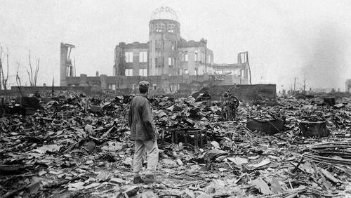 This Sept. 8, 1945, picture shows an Allied correspondent standing in the rubble in front of the shell of a building that once was a movie theater in Hiroshima, Japan, a month after the first atomic bomb ever used in warfare was dropped by the U.S. (AP Photo/Stanley Troutman)