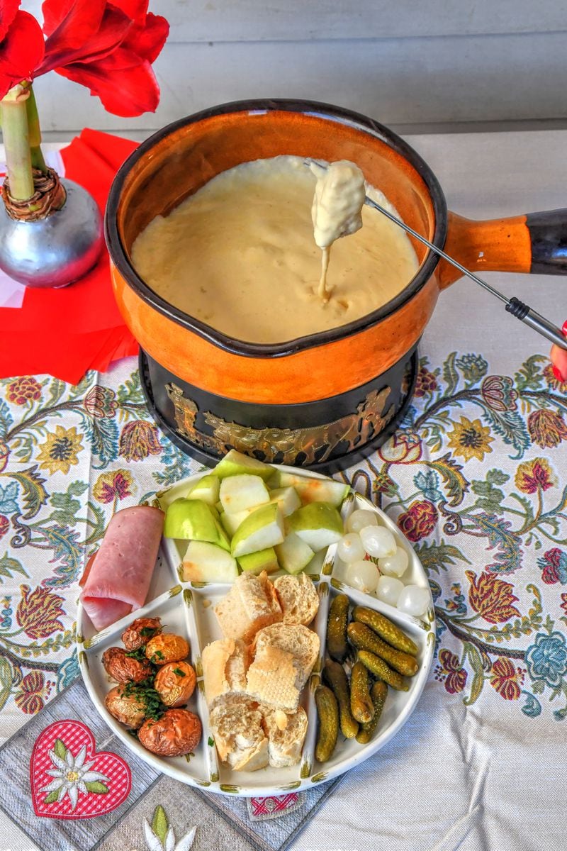 Classic Cheese Fondue can be served with charcuterie, roasted potatoes, sliced apples, crusty bread, gherkins and pickled onions. (Styling by Lisa Hanson / Chris Hunt for the AJC)