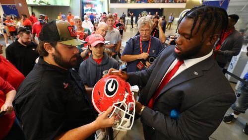 Georgia center Sedrick Van Pran autographs a helmet for a Georgia fan as he arrives at SEC Media Days in the College Football Hall of Fame on Wednesday, July 20, 2022, in Atlanta.  Curtis Compton / Curtis Compton@ajc.com