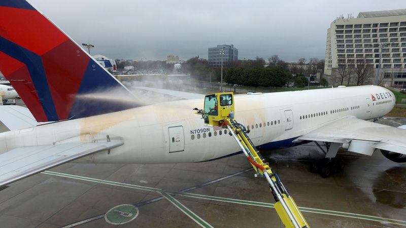 A Delta worker demonstrates how to spray a colored deicing solution on the entire plane before it can take off. 