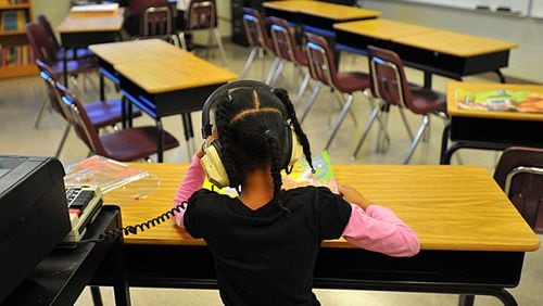 A Burgess-Peterson Elementary School student listens to an audio book as she reads along. In the wake of the cheating scandal, the Atlanta Public Schools system is expanding programs, such as this one at Burgess-Peterson, to help students who need extra assistance to keep up. The potential cost of the expanded remediation program is $6.4 million.