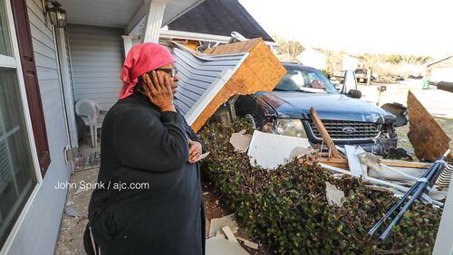 Carolyn Burgess surveys the damage after a stolen car crashed into her Browns Mill Ferry Road home Friday morning.
