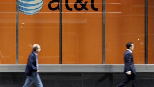 FILE - In this Tuesday, Oct. 21, 2014, file photo, people pass an AT&T store on New York's Madison Avenue. (AP Photo/Richard Drew, File)