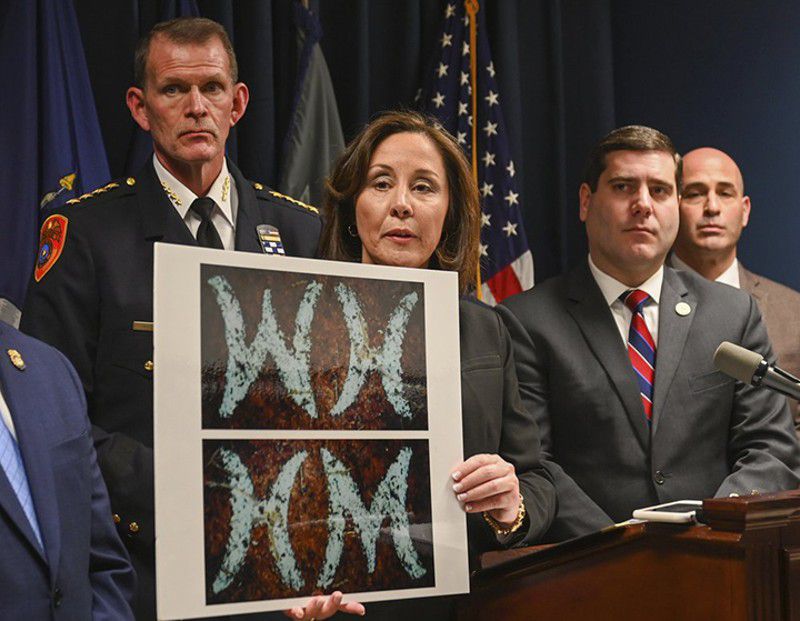 Suffolk County Police Commissioner Geraldine Hart shows a photograph with the initials on a belt, showing either an HM or WH, depending on the angle, during a news conference at police headquarters in New York.