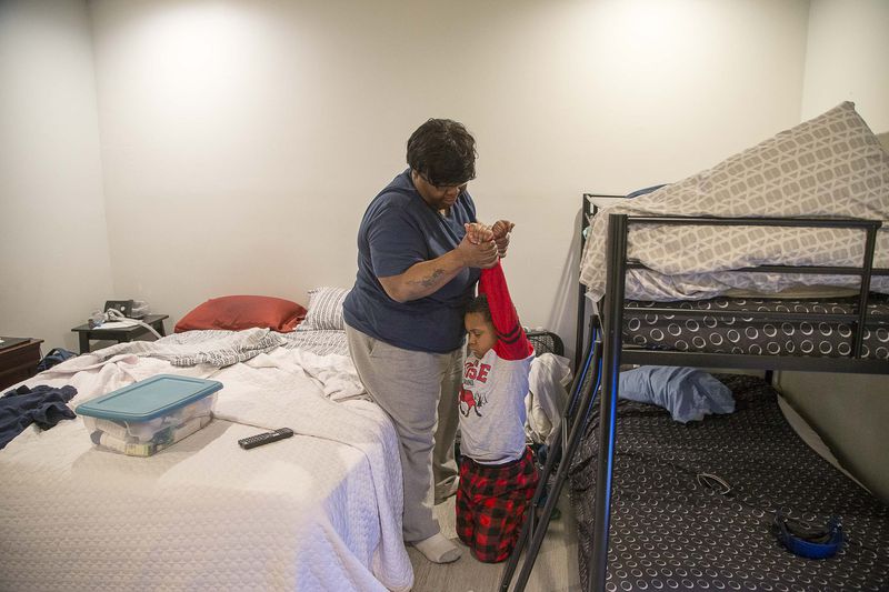 Pearl Lilly attempts to get her grandson, Corbin, out of bed so that he can get ready for school on Wednesday, Feb. 26, 2020. (ALYSSA POINTER/ALYSSA.POINTER@AJC.COM)