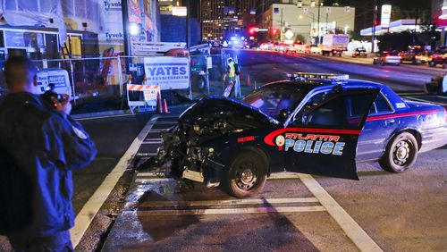 An Atlanta Police Department crime scene technician takes pictures (left) after an accident involving an Atlanta police officer and another car at 10th and Williams Streets in downtown Atlanta on Sept. 25, 2012.