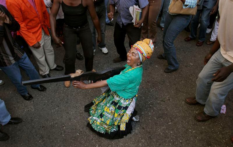 FILE — A woman pretending to fire a mock weapon joins supporters of former deputy president Jacob Zuma in protest outside the High Court in Johannesburg, Wednesday, April 5, 2006 during Zuma's rape trial. For the first time since 1994, the ruling African National Congress (ANC) might receive less than 50% of votes after Zuma stepped down in disgrace in 2018 amid a swirl of corruption allegations and has given his support to the newly-formed UMkhonto WeSiizwe political party. (AP Photo/Denis Farrell/File)