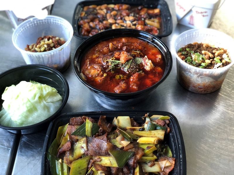 This takeout order from Urban Wu includes: (clockwise from top) kung pao chicken, dan dan noodles, double-cooked Sichuan pork, lettuce wraps; and (center) fish braised in chili oil. CONTRIBUTED BY WENDELL BROCK
