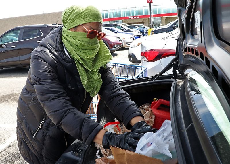 Ernnee Webber wears a scarf over her head and face and gloves as she puts her groceries in the trunk of her car Friday at Meijer in Springfield. Webber said she tried to find some medical masks but every place was sold out so she made her own. BILL LACKEY/STAFF