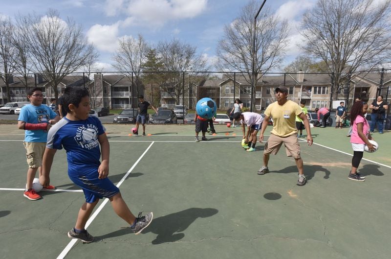 Daniel Pina (foreground), 10, and his father Antonio Pina play during a soccer event hosted by YELLS (Youth Empowerment through Learning, Leading, and Serving, Inc.) to promote community engagement on Franklin Gateway HYOSUB SHIN / HSHIN@AJC.COM