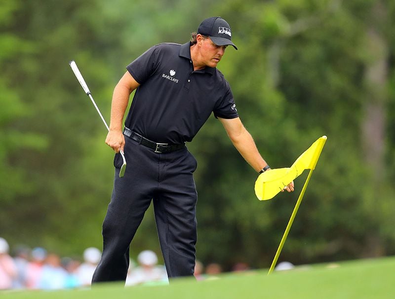 Phil Mickelson pulls the flag from the 8th green during the final round at the Masters Golf Tournament, Sunday, April 12, 2015, in Augusta.