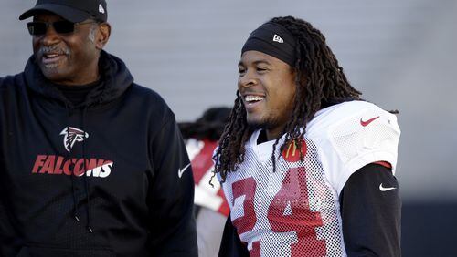 Atlanta Falcons running back Devonta Freeman (24) smiles as he talks with assistant coach Bobby Turner during a practice at the University of Washington Wednesday, Oct. 12, 2016, in Seattle. Rather than head home, the team traveled directly to Seattle after a football game Sunday in Denver, ahead of playing the Seattle Seahawks this coming Sunday in Seattle. (AP Photo/Elaine Thompson)