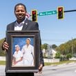 Deonté Smith stands under a street sign dedicated to his great grandmother and great-great grandmother while holding a painting of them in McDonough. (Atlanta Journal-Constitution/Jason Allen)
